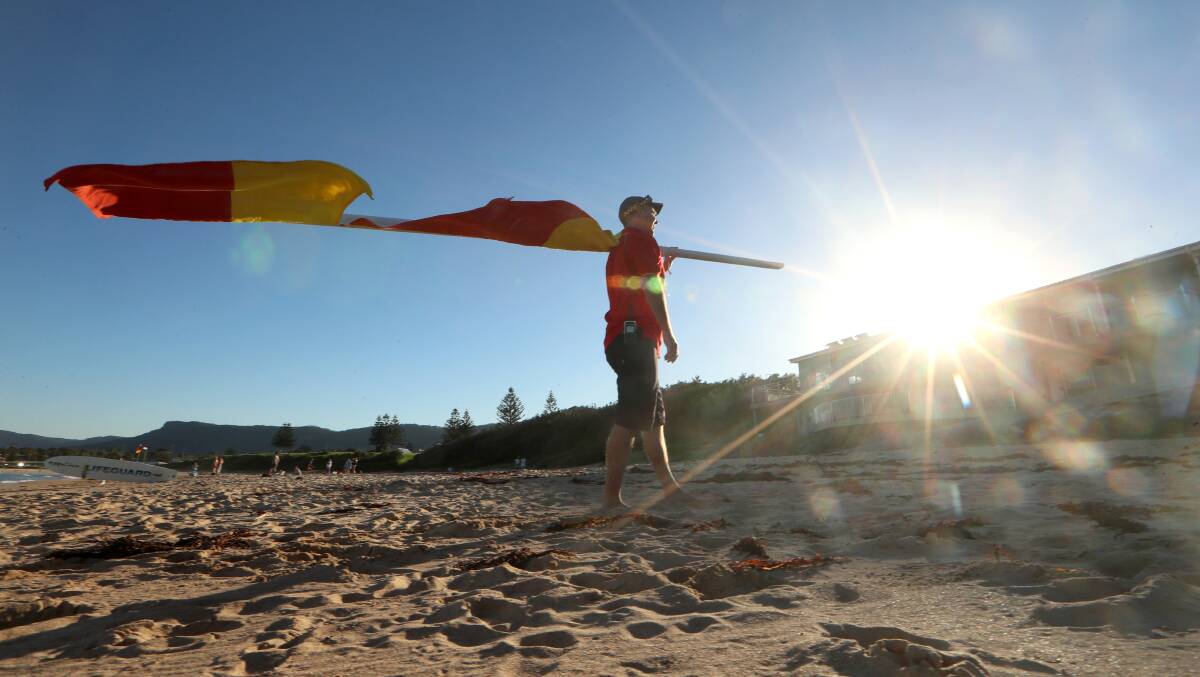 Season's end: SLSI duty officer Anthony Turner gets ready to pack up the red and yellow flags to mark the end of the surf patrol season on Sunday. Picture: Sylvia Liber