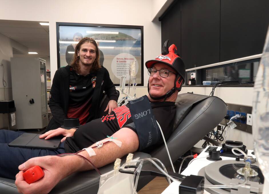 HELPING OUT: Illawarra rookie Sam Froling and Hawks fanatic Graham Lancaster support the Red Cross RED25 Unite To Save Lives campaign. Picture: Robert Peet