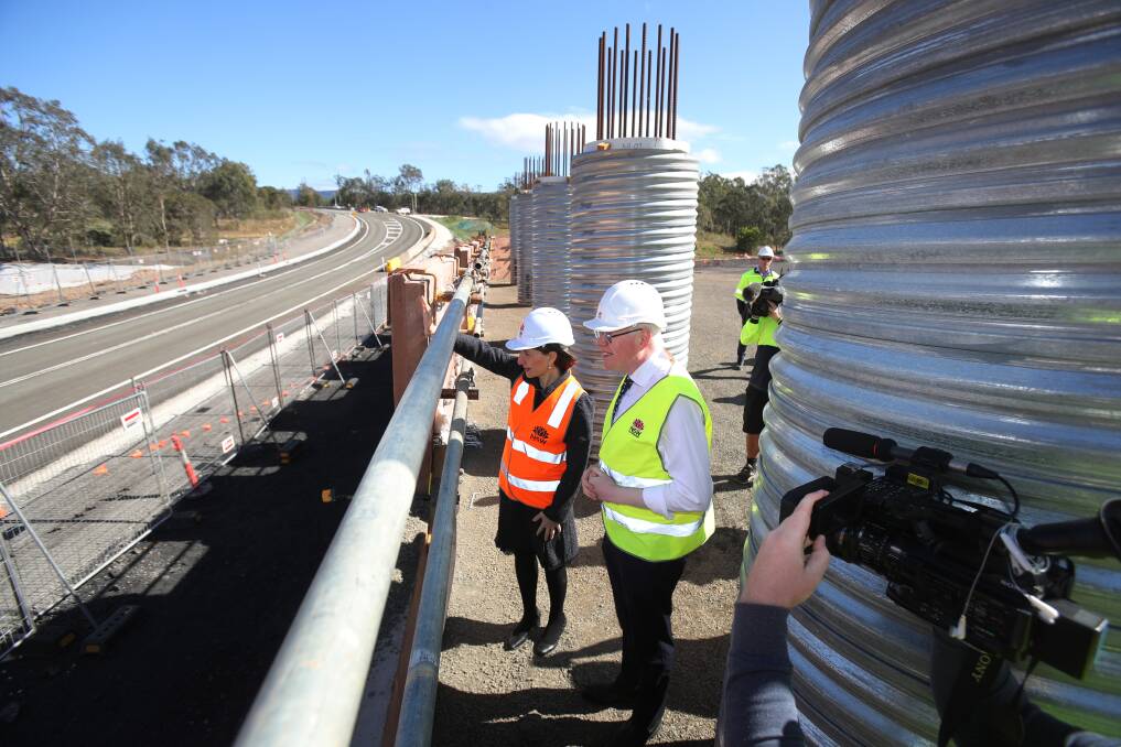 NSW Premier Gladys Berejiklian and Kiama MP Gareth Ward wave to motorists passing along the new Yallah Road - built as part of the Albion Park Rail bypass. Picture: Robert Peet