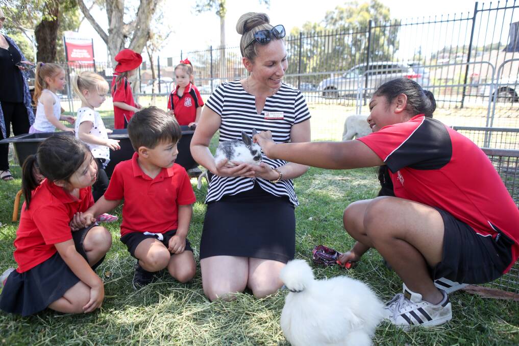 CELEBRATIONS: Kemblawarra Public School principal Rebeka Schroder in the petting zoo with students Lindsey, Sonny and Sama. The school held a market day on Wednesday to celebrate its 60th anniversary. Picture: Adam McLean.