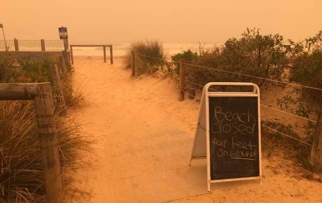 A sign notifying people Pambula Beach had closed as the sky turned orange on Tuesday. Picture: Kimberley Le Lievre