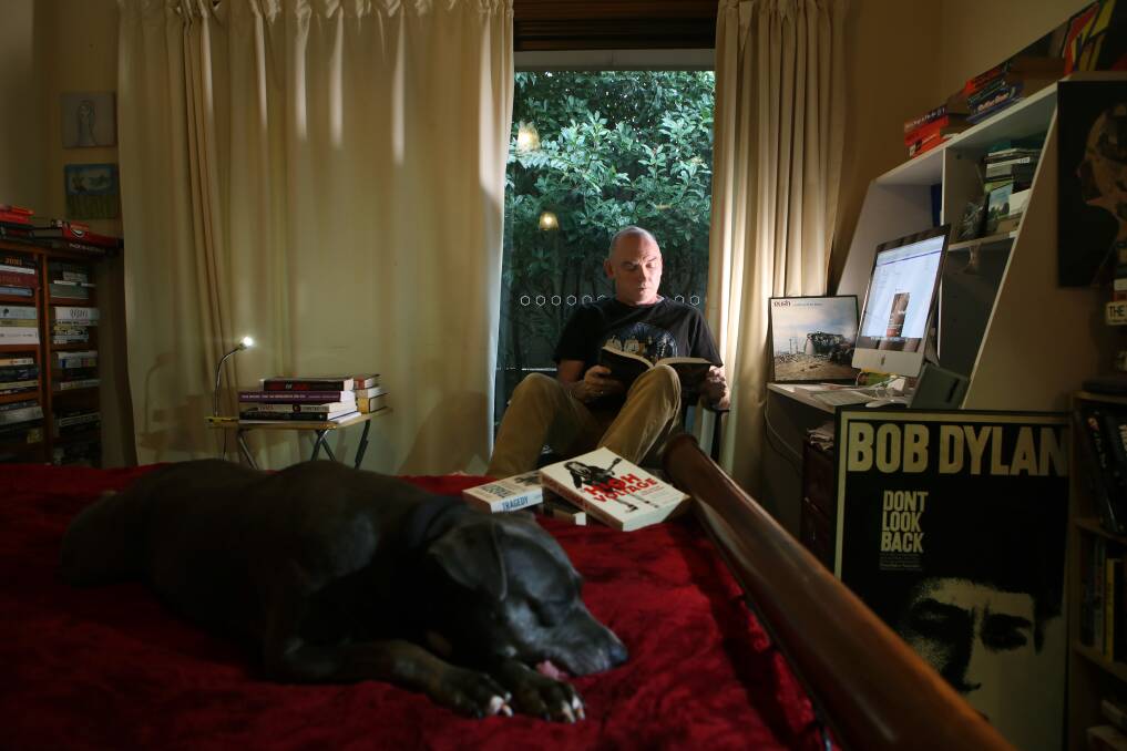Working: Keiraville author Jeff Apter hard at work in the home office, while family dog Neela takes it easy. Picture: Sylvia Liber