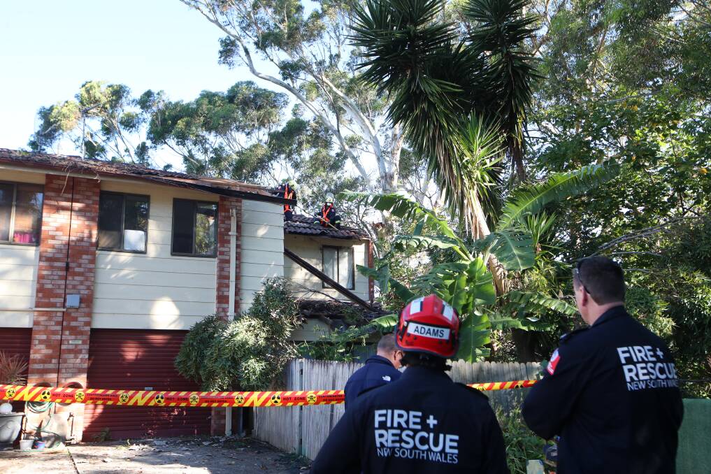 Fire and Rescue NSW crew work on the roof of a Balgownie townhouse after a tree branch crashed through it. Picture: Sylvia Liber