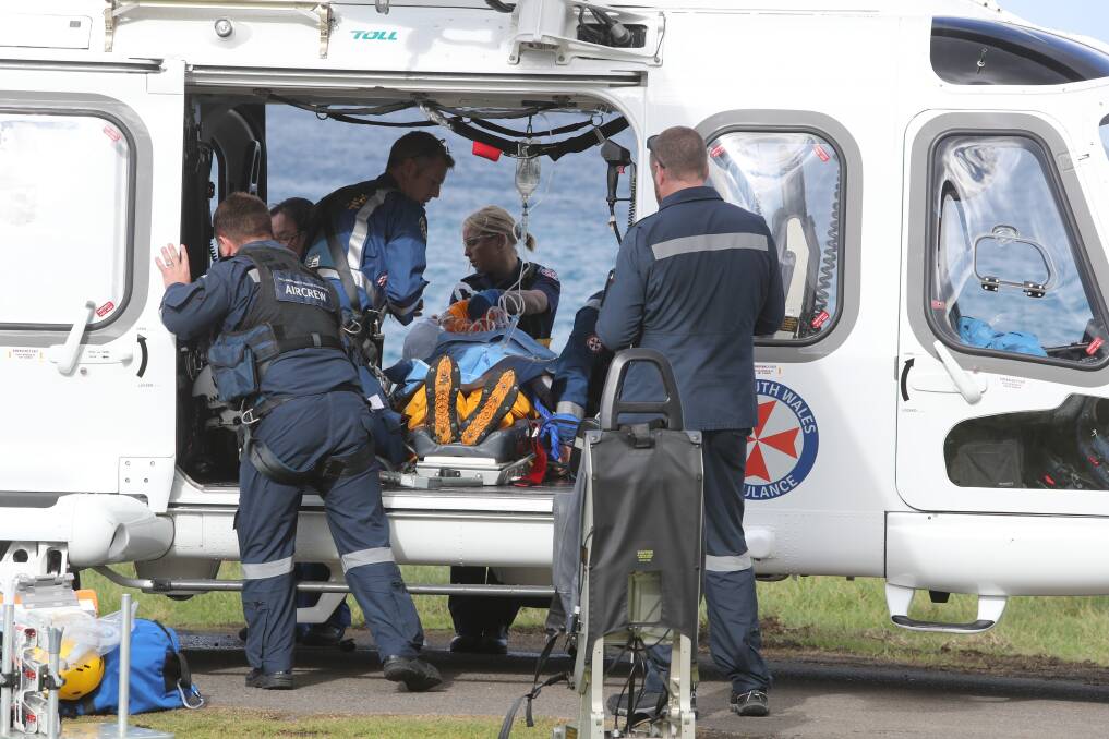 RESCUE: Paramedics treat the fisherman at Wombarra before he was flown to St George Hospital. Picture: Robert Peet.