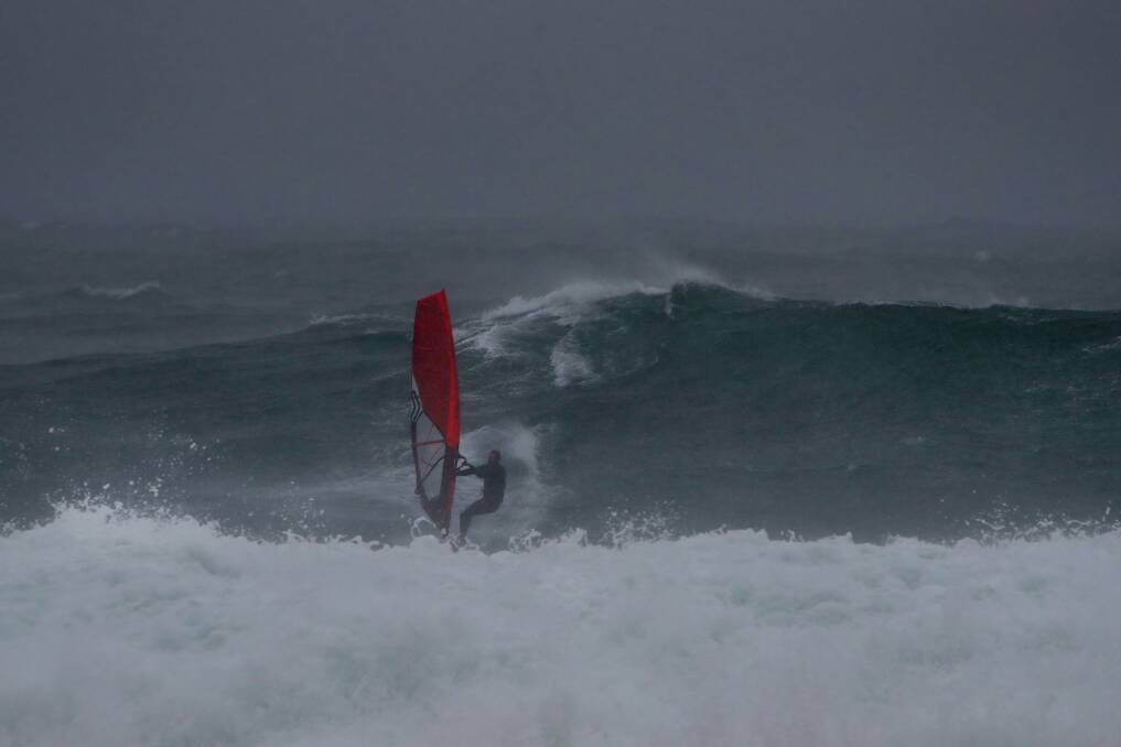 A windsurfer braves the big swell at Shellharbour Sunday afternoon. Picture: Sylvia Liber