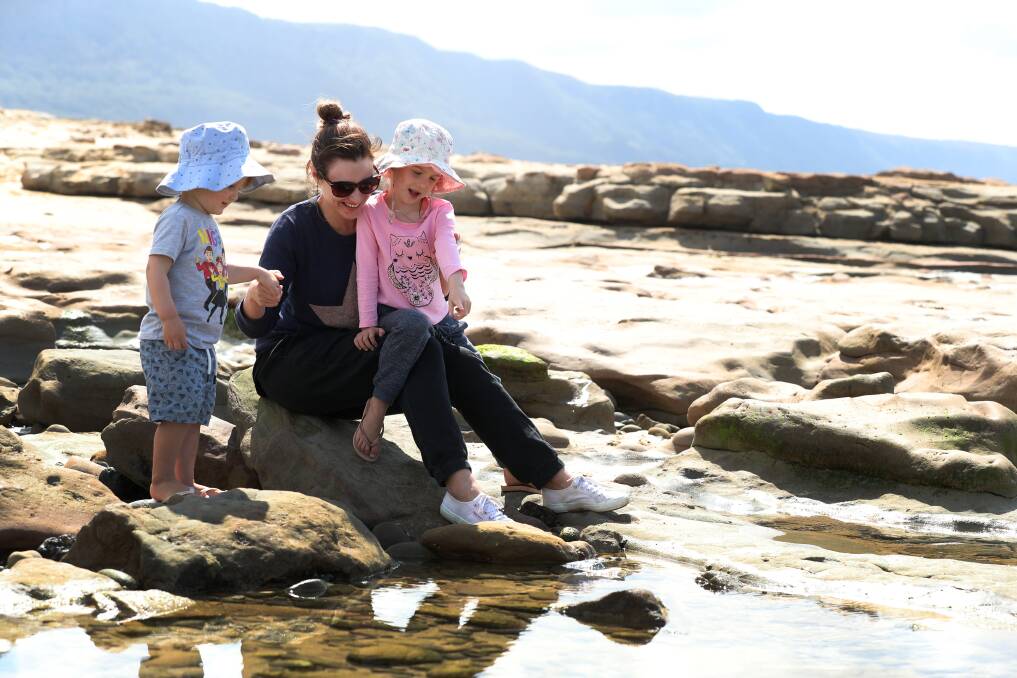 Thirroul resident Karina Stuart-Street playing in the Sandon Point rock pools with her children Henry and Ruby on Tuesday. Picture: Robert Peet