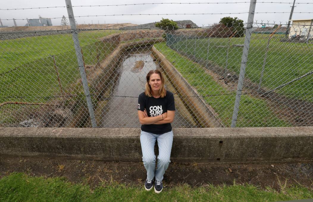 Port Kembla resident Jess Whittaker, at the drain where it passes under Foreshore Rd, asked why if pollution had been expected, it had not been monitored. Picture by Robert Peet.