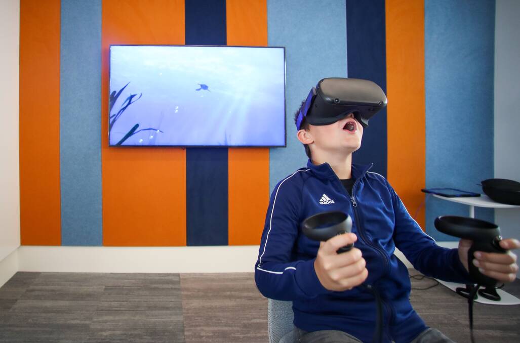 Warilla has a purpose-built library - 10 year old Emre Ahishali tries out a virtual reality headset in the tech room. Photo: Adam McLean