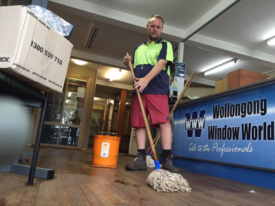 Sogged again: Haydn Atkins mops up at Wollongong Window World, which got about 25cm of water through the premises. Pictures: Ben Langford.