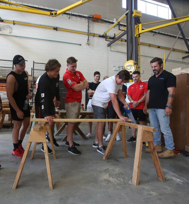In the groove: Brett McCroary (right) with the nine young Dragons rookies in the carpentry school at TAFE. Pictures: Robert Peet