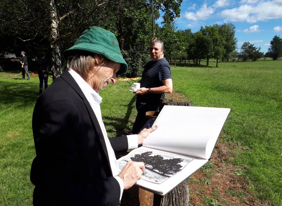 HIGH ART: Reg Mombassa sketching in a Southern Highlands paddock while Euan Macleod looks on. Their work will help fund the anti-mine fight.