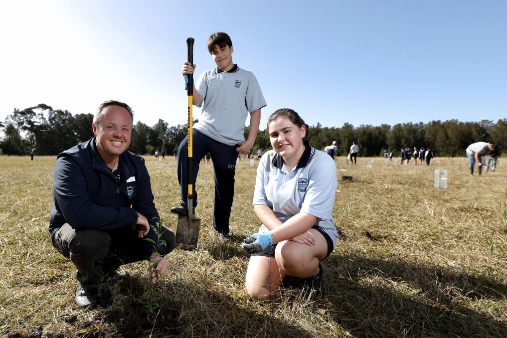 60 TREES GREENER: Corrimal High geography teacher Ben Spooner with Year 7 students Eduardo Couto and Paige Rzmeinski planting some trees. Picture: ADAM McLEAN.