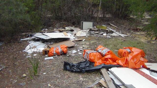 DISGRACE: The remnants of someone's old kitchen have been illegally dumped down a fire trail near Helensburgh, with likely asbestos waste in the orange plastic. Source: Alan Bond.