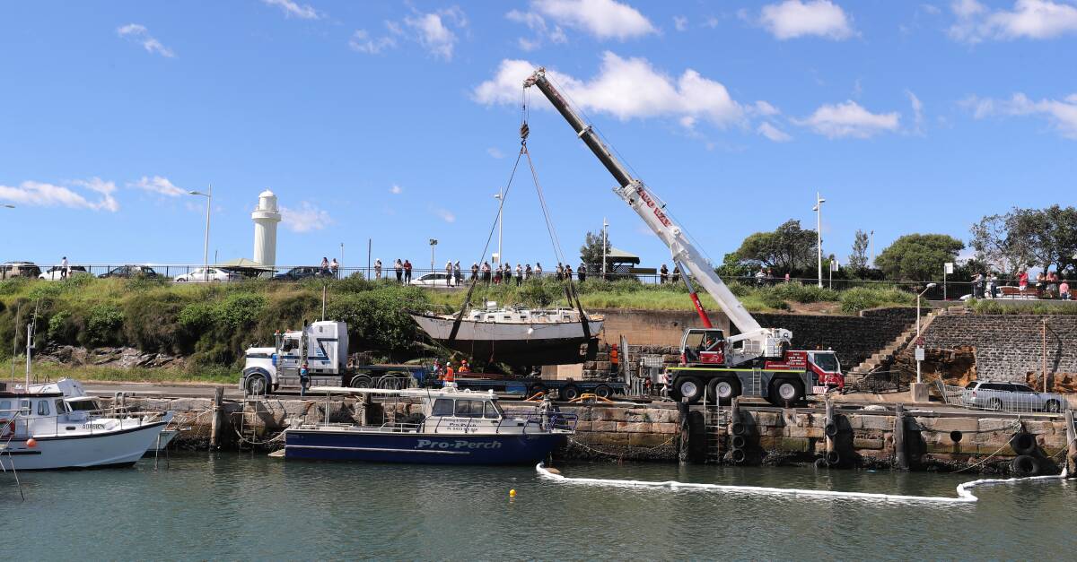 HEAVE HO: A crane lifts the stricken 9m yacht from the water and onto a truck at Wollongong Harbour about 11am on Wednesday. Pictures: ROBERT PEET.