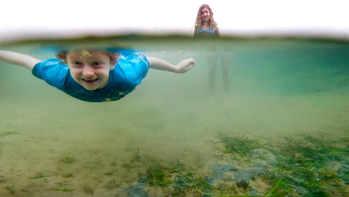 Dive master: Ronan Duggan dives under the water in a rock pool at Austinmer while his sister Marin watches on. Picture: Sylvie Liber