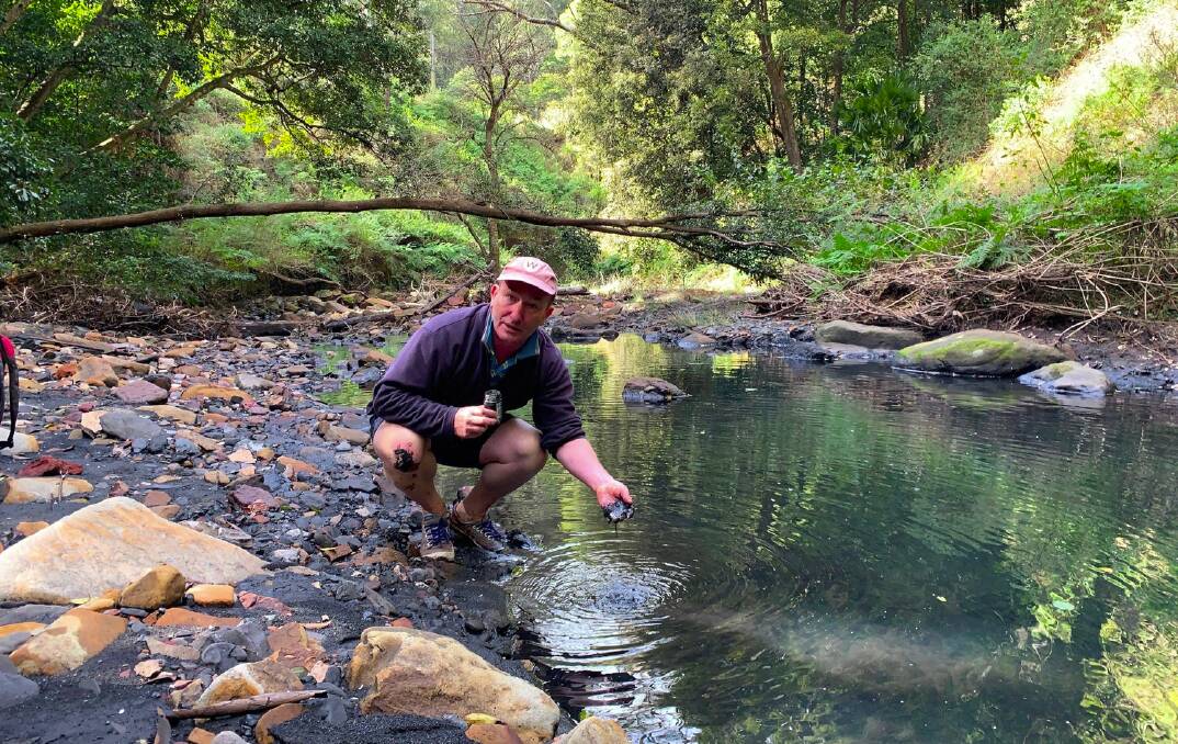 Scientist Dr Ian Wright gets his hands in some of the coal sludge which befouled Camp Gully Creek. Picture supplied.