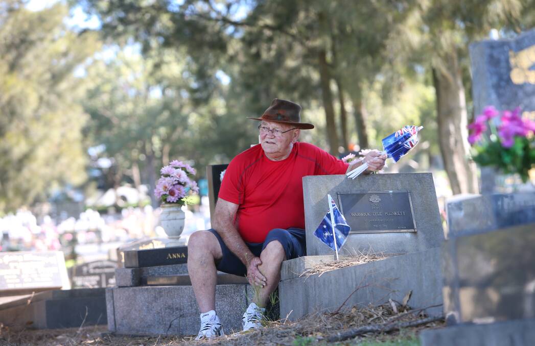RECOGNITION: Don Briggs placing Australian flags at the graves of each former service member at the Shellharbour cemetery on Wednesday. Picture: Sylvia Liber.