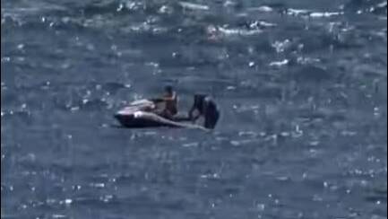 A passerby rescues a fallen jet ski rider near Windang Island, as seen in this still from footage taken by a witness, Jess.