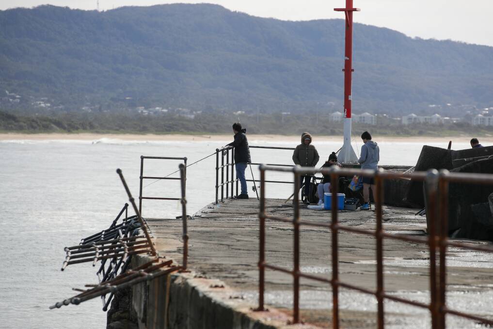 Fishers on the breakwall at Wollongong Harbour on Tuesday, where fencing remains broken. Picture: Adam McLean