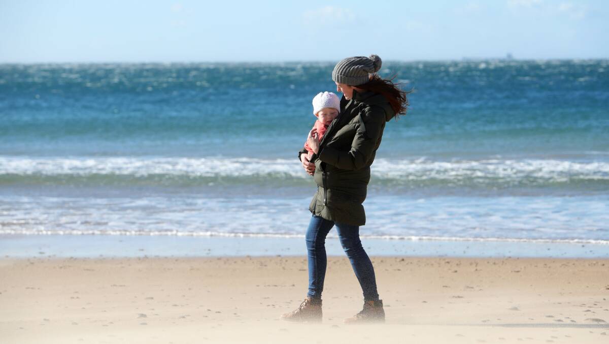 Phoenix Bliesner and her daughter Flori brave the winds down at North Wollongong Beach on Monday morning. Picture: Sylvia Liber