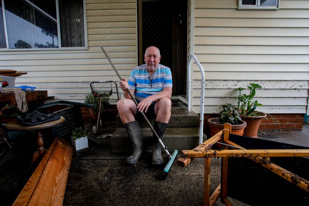 Robert Summers sits on the back steps of his flooded house in south Wollongong. Picture: Wesley Lonergan