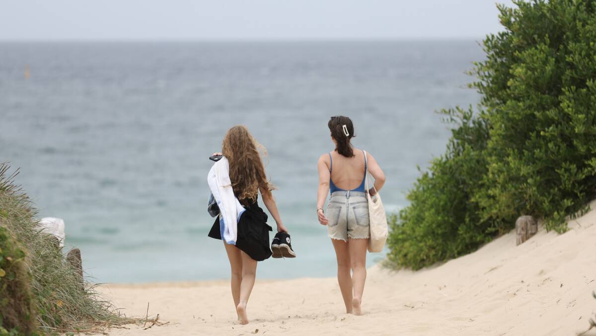 Two young women head down to the beach on a warm but overcast day in Wollongong. Picture by Adam McLean