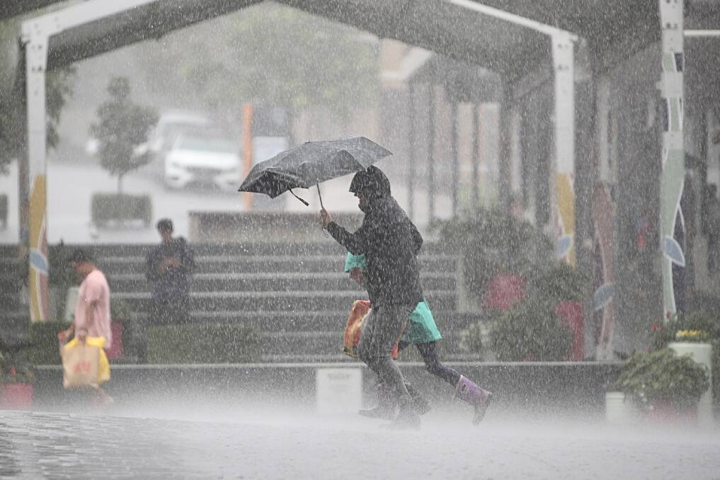 RUN FOR COVER: A shopper hurries to escape the rain in Crown Street Mall on Saturday. Picture: Adam McLean