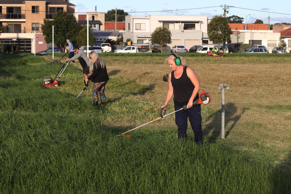 Corrimal Netball Club president Joedy Petre and other helpers tackle the grass at Guest Park in Fairy Meadow. Picture: Robert Peet