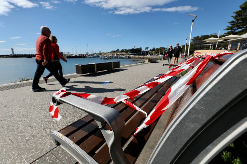 KEEP MOVING: People walk by benches at Belmore Basin that have been taped off to stop people stopping and congregating during lockdown. Picture: Adam McLean