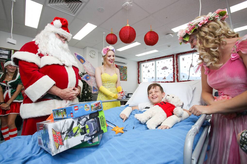 Welcome gift: Santa Claus, the KidzWish fairy and Fairy Flora bring some Christmas cheer to Liam Nyers-Saunders at Wollongong's children's ward. Picture: Adam McLean