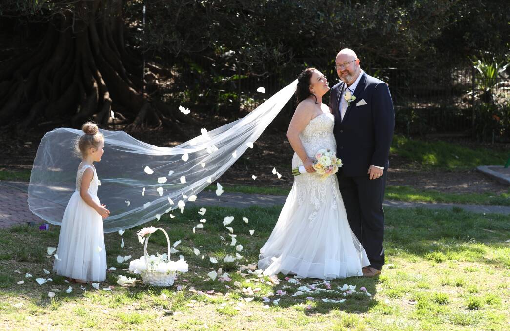 Small wedding: Brad Foye with his new wife Melissa Moore and her flower girl daughter Alana Moore, 5, at Shellharbour Village on Wednesday. Picture: Robert Peet