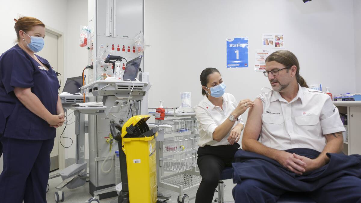 Immunisation co-ordinator Natasa Veselinovic administers the vaccine to security staff member David Nichols.