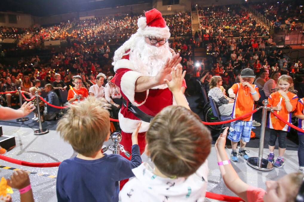 Annual celebration: High fives for Santa at the 2018 KidzWish Christmas party at the WIN Entertainment Centre. Picture: Adam McLean