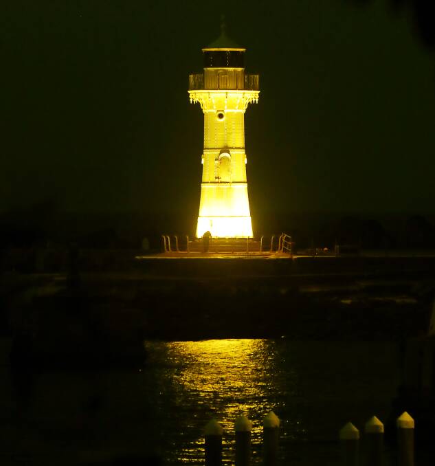 Stay safe: The lighthouse on the Wollongong Harbour breakwater is lit up in yellow on Thursday night as a reminder of National Road Safety Week. Picture: Robert Peet 