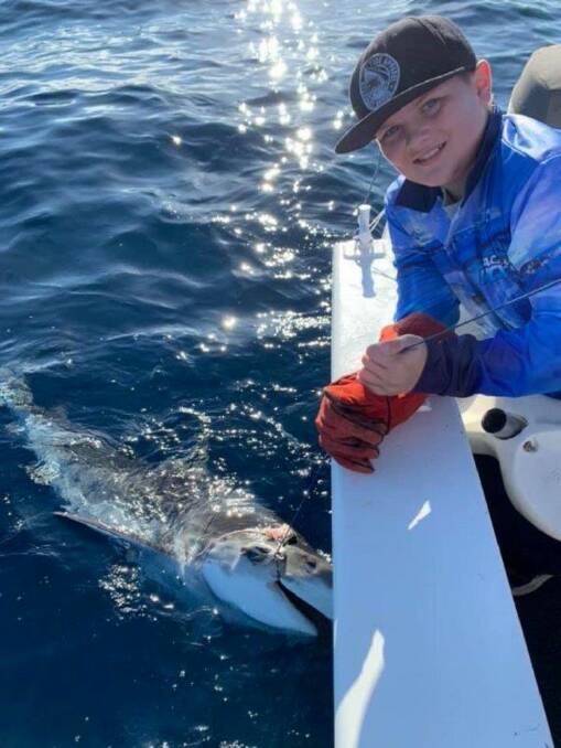 Back you go: Mason McDonough holds the trace on his tiger shark just before tag and release.