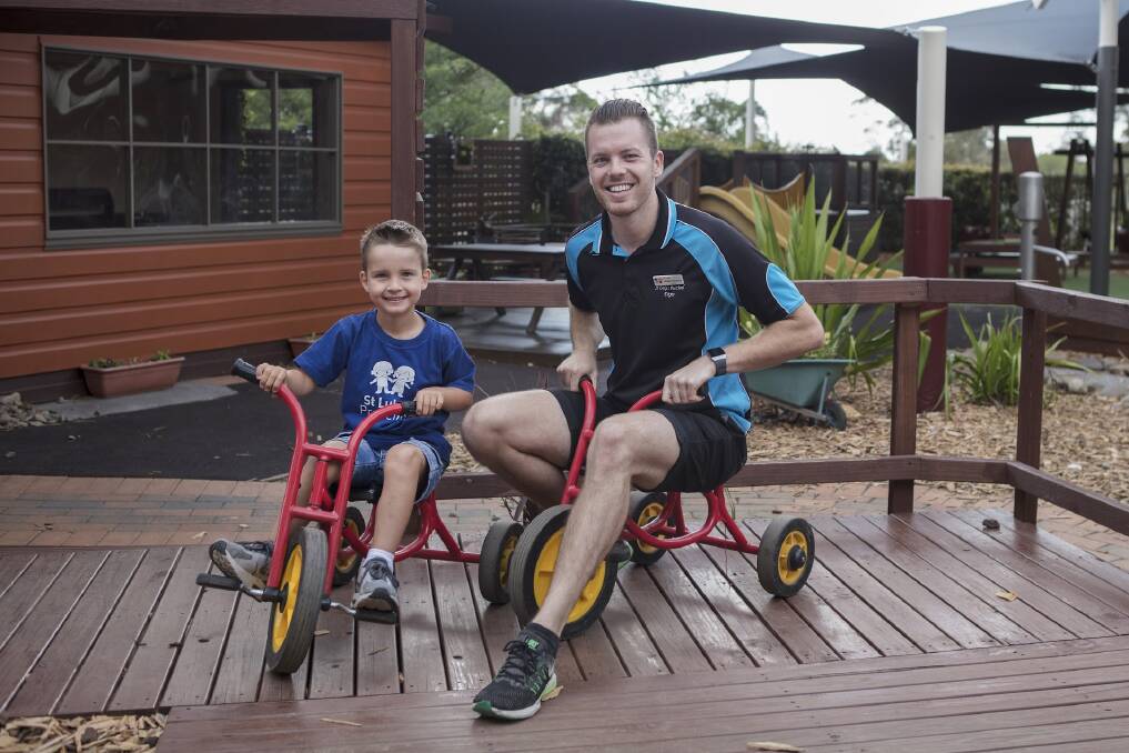 CARING KIND: Educator Blake Stewart with one of the children at St Luke’s Preschool in Dapto.  Picture: Nina Photography