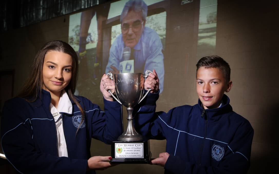 HONOURING THE LATE LES MURRAY: Illawarra Sports High School students Liliana Spiroski and Thomas Cleverly hold aloft the Les Murray Cup. The school held a special ceremony to honour the late broadcaster. Picture: Sylvia Liber