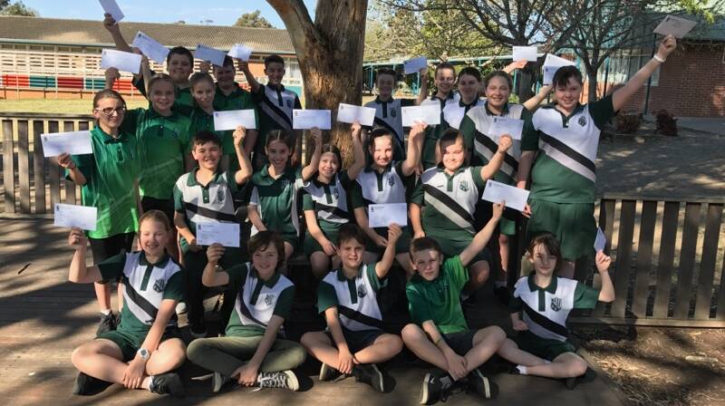 WAR ON WASTE: Albion Park Public School students hold aloft the letters they have written to businesses, families and high schools as part of their war on waste campaign. Picture: Supplied