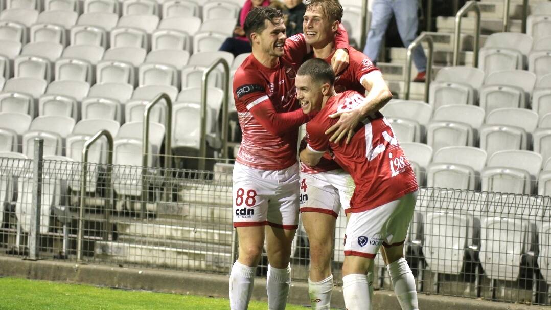 Wollongong Wolves team-mates hug Jake Trew after the striker scored his first of two goals in their 2-2 draw with Sydney Olympic at WIN Stadium on Sunday. Picture by Pedro Garcia.