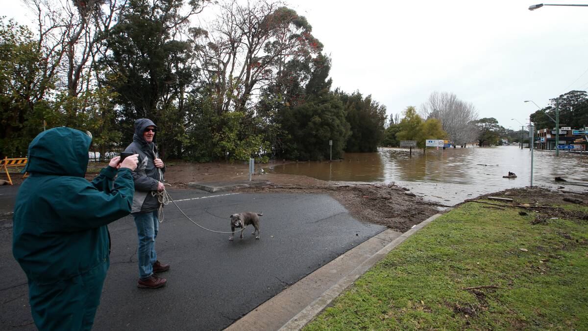 Residents survey the flooding at the intersection of Meroo Street and Bolong Road at Bomaderry on Monday. 