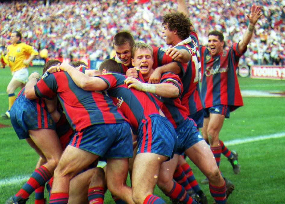 Newcastle's Darren Albert (centre) is mobbed and congratulated after his match winning last gasp try in the 1997 grand final. Picture: Rob Cox/Action Photographics