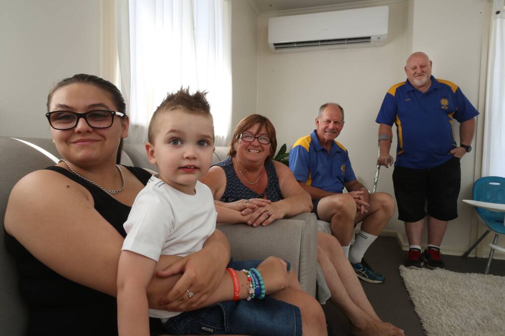 DONATION: Leteisha and Hunter with their nan Carol Sinclair, and Gary Flint and Steven Sherwood from Oak Flats Lions Club, following the installation of the air conditioner. Picture: Robert Peet