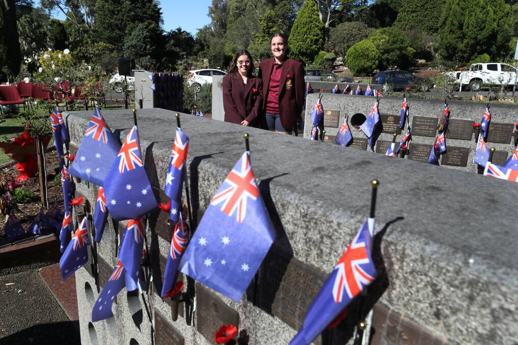 CEREMONY: Dapto High School students Kayla Varir and Brodee Beattie with flags placed by students at the Wollongong Memorial Gardens. Picture: Robert Peet