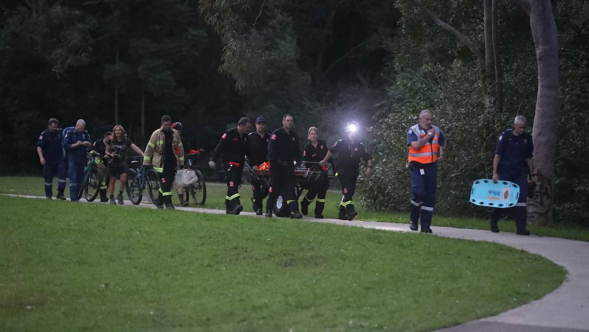 Emergency services retrieve an injured mountain bike rider from bushland in Balgownie on Monday.