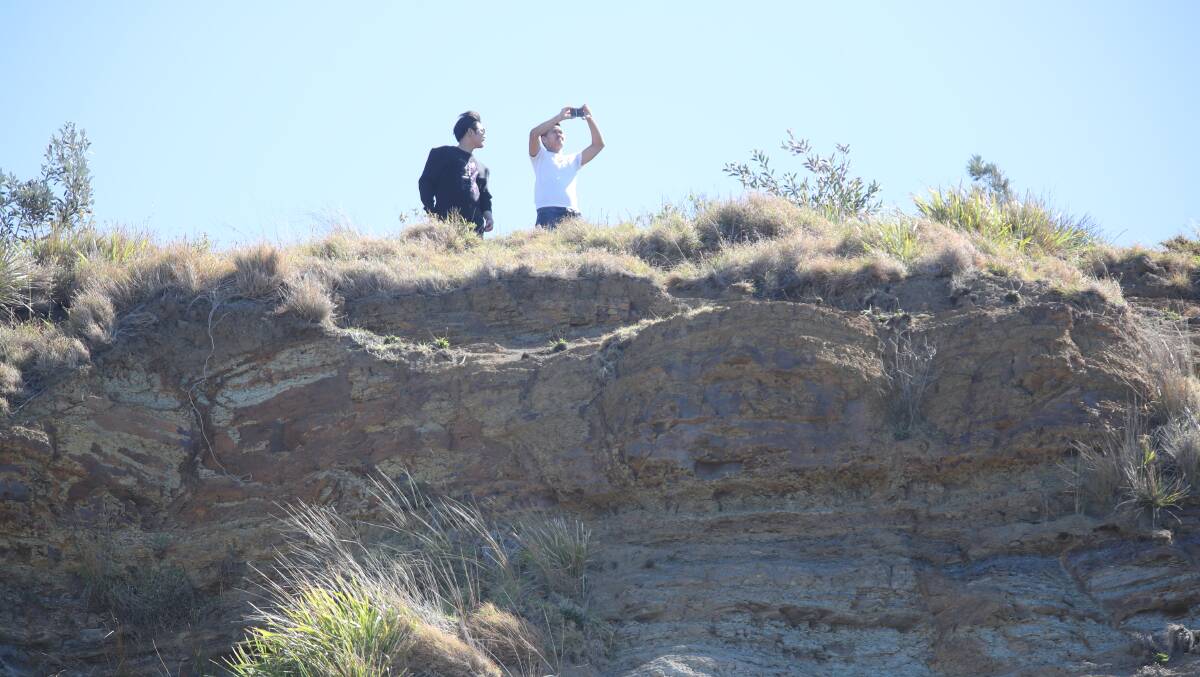 Two people pose for a photo at Sea Cliff Bridge just 48 hours after a man fell to his death at the same location. Picture: Adam McLean
