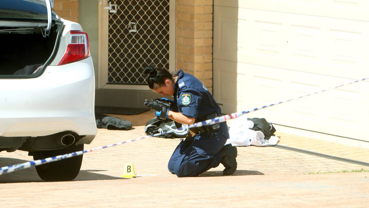 A forensic investigator takes photos at the scene of an alleged shooting in Horsley on Friday. Photo: Sylvia Liber