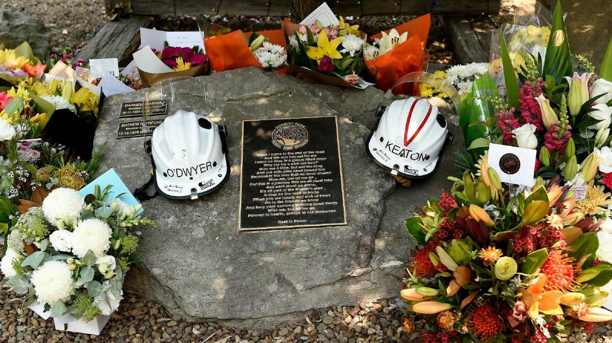 Flowers and the helmets of volunteer firefighters Andrew O'Dwyer and Geoffrey Keaton are seen at a memorial at the Horsley Park Rural Fire Brigade. Photo: AAP