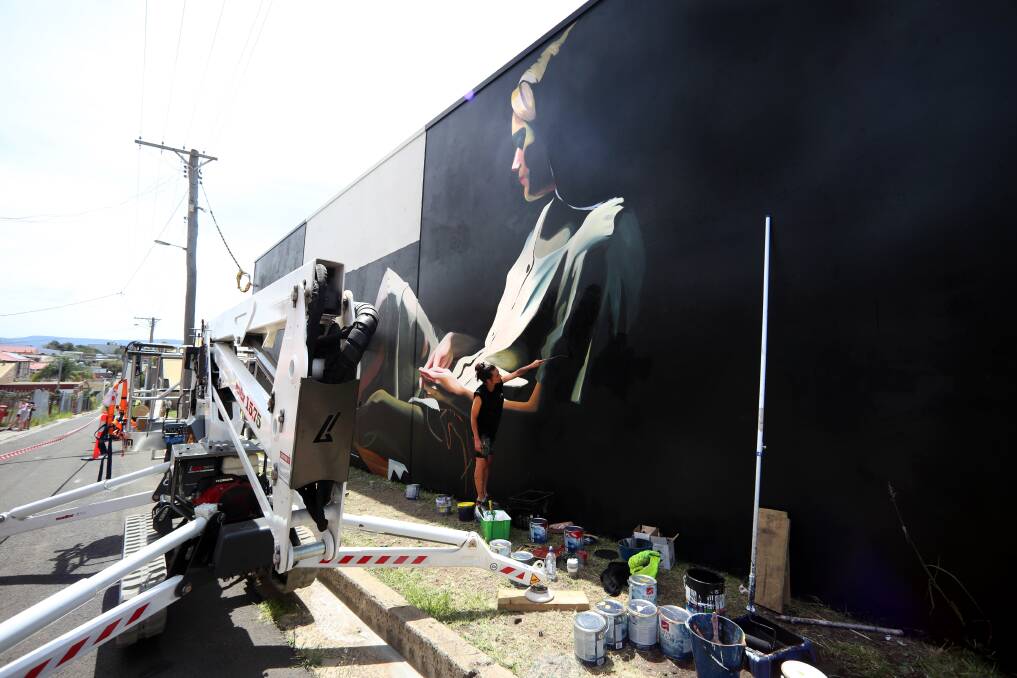 Loretta Lizzio works on her artwork, located along Military Lane, on Saturday afternoon.