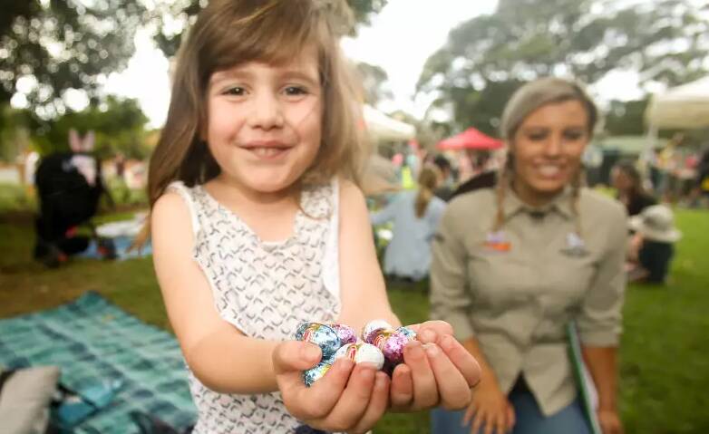 A file image of a young girl holding a handful of tiny Easter eggs.