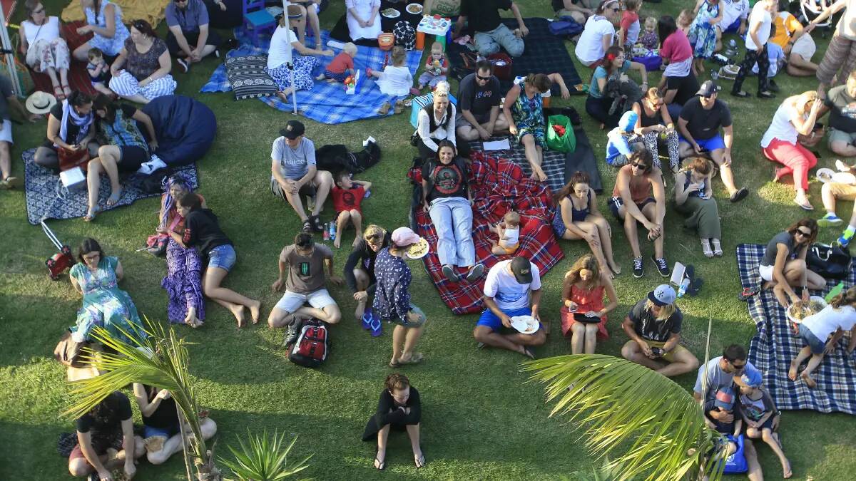Market-goers picnic on the grass at Bulli Showground.
